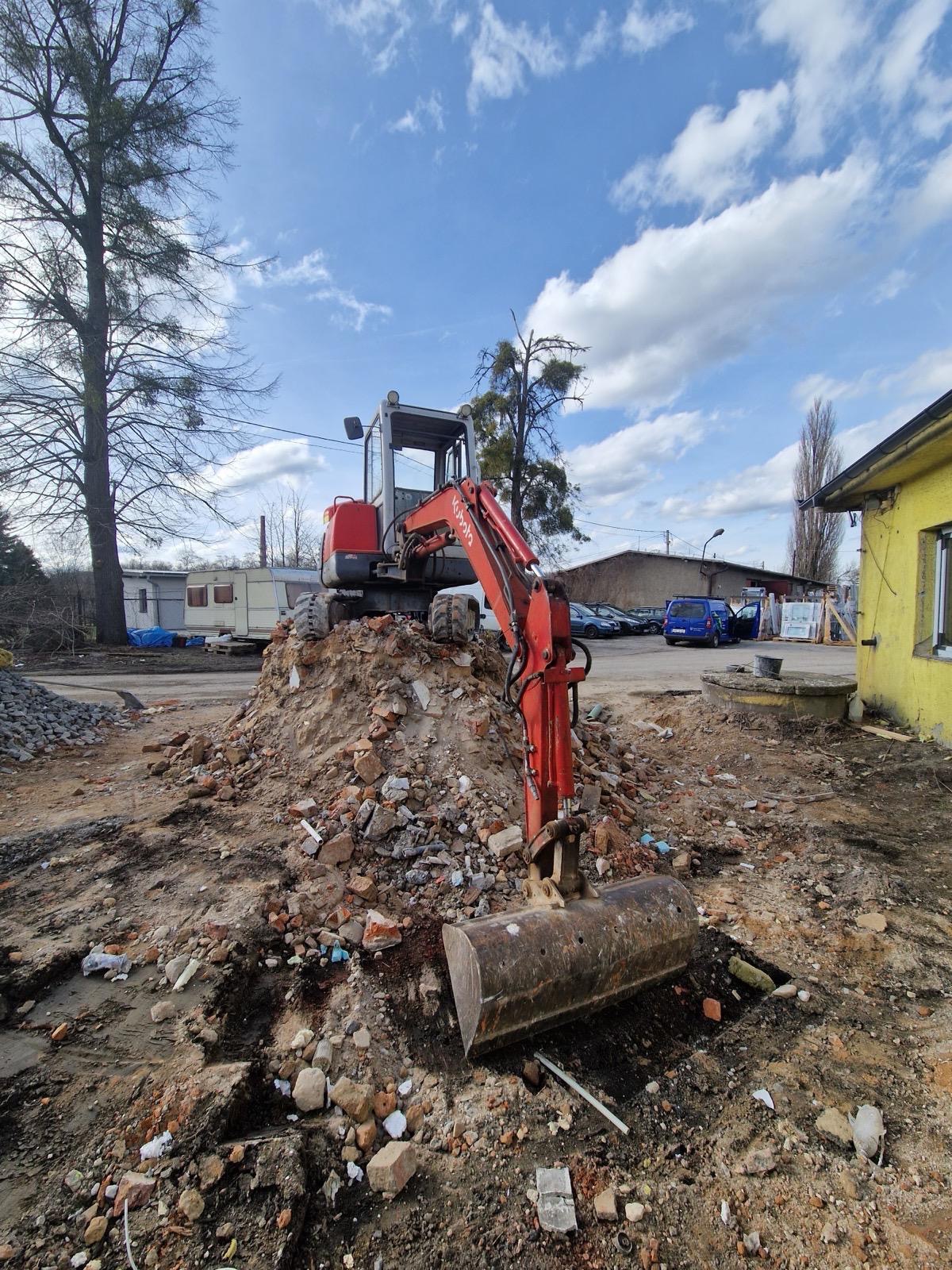 Rypadlo Kubota na hromadě suti